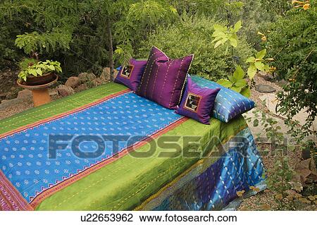 Stock Image - Colorful bedding on outdoor bed. Fotosearch
