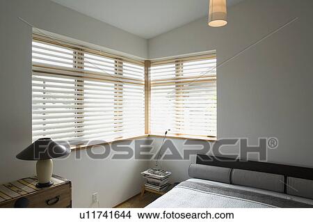 Picture - Contemporary bedroom with gray bed and corner windows. Fotosearch