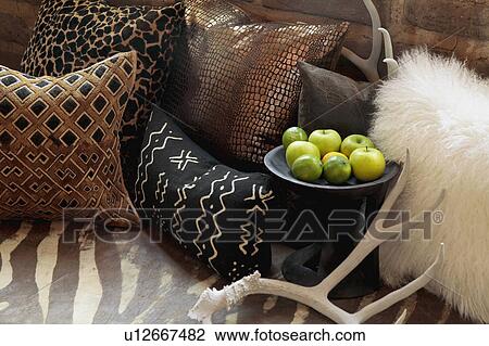 Stock Image - Decorative throw pillows, antlers, and apples on bed. Fotosearch