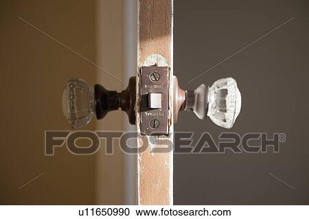 Stock Image - Detail glass doorknob in wooden door. Fotosearch