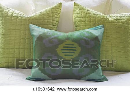 Stock Image - Detail green throw pillows on bed. Fotosearch