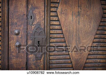 Stock Image - Detail wooden door with intricate keyhole. Fotosearch