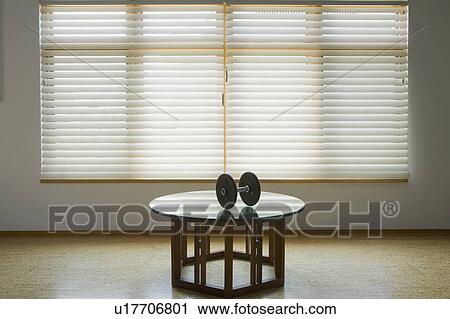 Stock Image - Dumbbell on table below window. Fotosearch