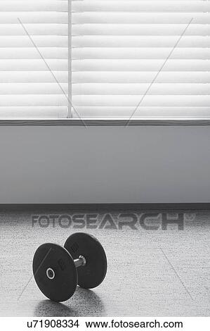 Picture - Dumbbell on wooden floor below window. Fotosearch