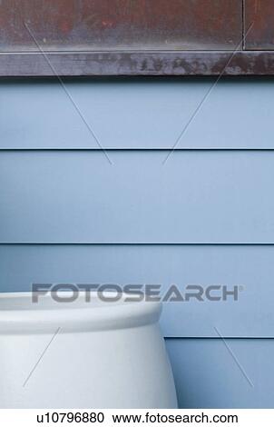 Stock Image - Large blue pot against blue sided home. Fotosearch