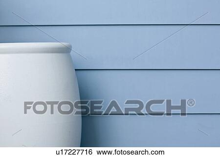 Stock Photograph - Large blue vase along blue siding. Fotosearch