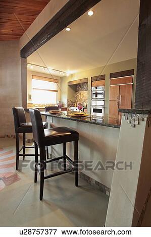 Stock Photo - Leather stools at breakfast bar in eco friendly home. Fotosearch