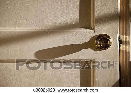 Stock Photo - Long shadow from the doorknob on the door. Fotosearch
