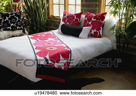 Stock Image - Pink floral accents on bed. Fotosearch