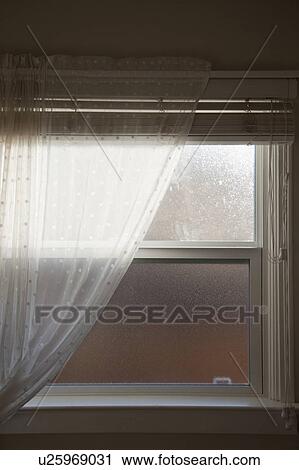 Stock Image - Sheer curtain in front of opaque bathroom window. Fotosearch