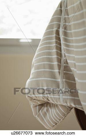 Stock Image - Striped blanket hanging off bed. Fotosearch