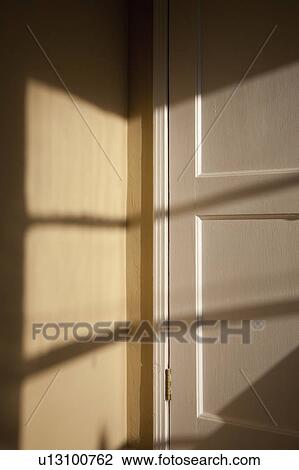 Stock Image - Sunlight streaming over the door and wall. Fotosearch