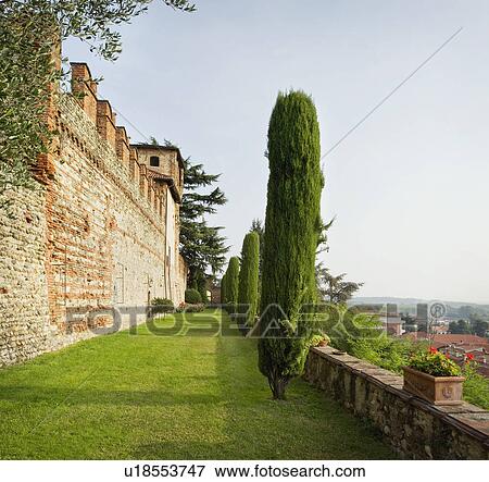 Stock Photo - Trees in yard along brick castle. Fotosearch