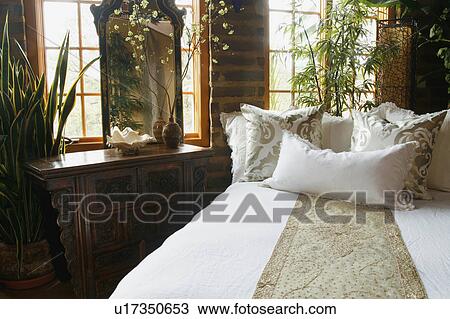 Stock Image - White and gold bed runner and pillows on bed. Fotosearch