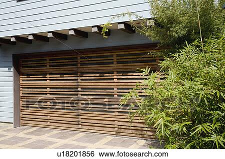 Stock Photograph - Wooden garage door and blue sided home. Fotosearch