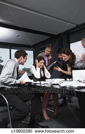 Stock Image - Business people screaming at a girl. Fotosearch