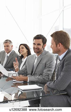 Stock Photo - Businesspeople sitting at a glass table. Fotosearch