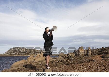 Stock Image - Businesswoman with a loud speaker. Fotosearch