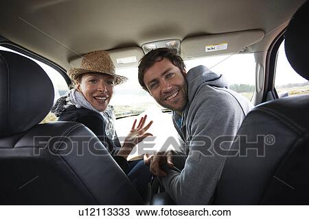 Stock Image - Couple looking at the back of a car. Fotosearch