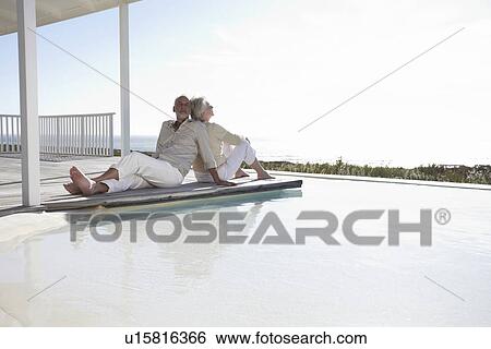 Couple relaxing at a pool View Large Photo Image Stock Photograph - Couple relaxing at a pool. Fotosearch