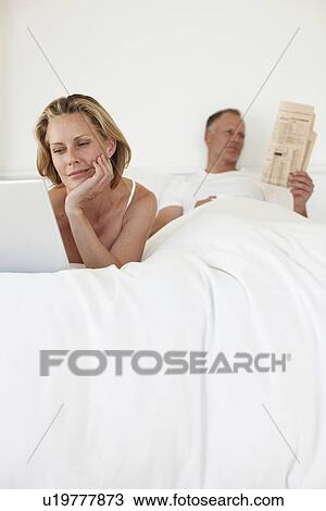 Stock Image - Couple relaxing in their bed. Fotosearch