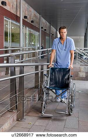 Doctor pushing a wheelchair View Large Photo Image Stock Photo - Doctor pushing a wheelchair. Fotosearch