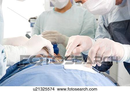 Doctors performing a surgery View Large Photo Image Picture - Doctors performing a surgery. Fotosearch
