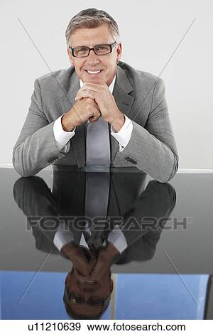 Executive sitting at a glass table View Large Photo Image Stock Photo - Executive sitting at a glass table. Fotosearch