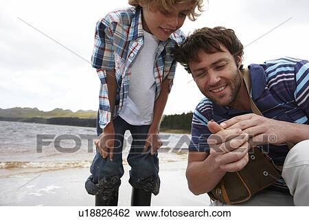 Stock Image - Father and son looking at ladybug. Fotosearch
