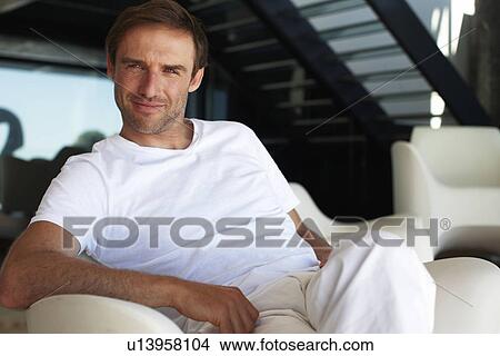 Man sitting on a chair View Large Photo Image Picture - Man sitting on a chair. Fotosearch