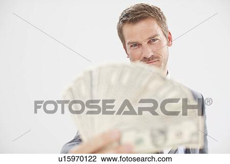 Stock Image - Man with a fan made of dollars. Fotosearch