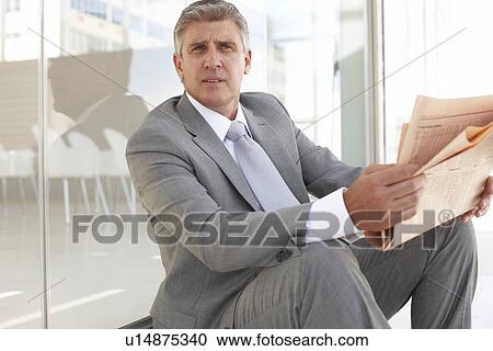 Stock Image - Mature businessman reading a newspaper. Fotosearch