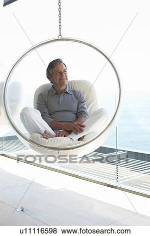 Stock Photo - Mature man sitting on a design chair. Fotosearch