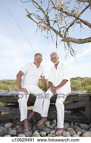 Stock Image - Men sitting under a tree. Fotosearch