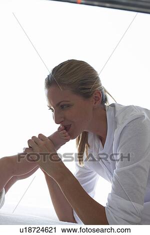 Stock Image - Mother kissing her baby's feet. Fotosearch