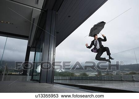 Stock Image - Successful man jumping in the rain. Fotosearch