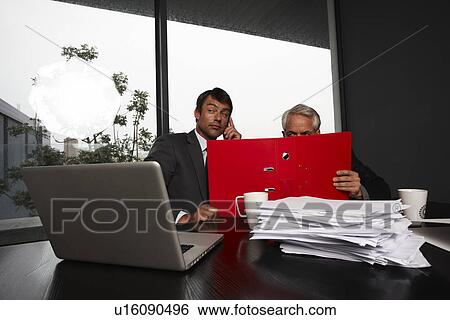 Stock Photograph - Two businessmen hiding behind a folder. Fotosearch