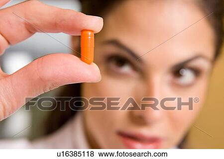 Stock Photo - Woman holding a pill. Fotosearch