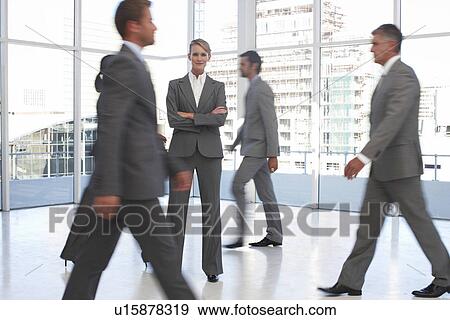 Woman standing among business people on the move View Large Photo Image Stock Photo - Woman standing among business people on the move. Fotosearch