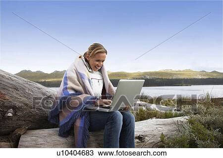 Stock Image - Woman with a laptop in the countryside. Fotosearch