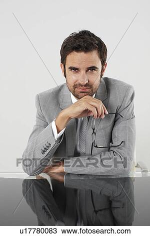 Stock Image - Young businessman sitting at his table. Fotosearch