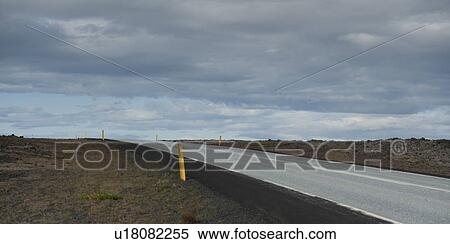 Stock Photography - Barren highway disappearing over horizon under a cloudy sky. Fotosearch