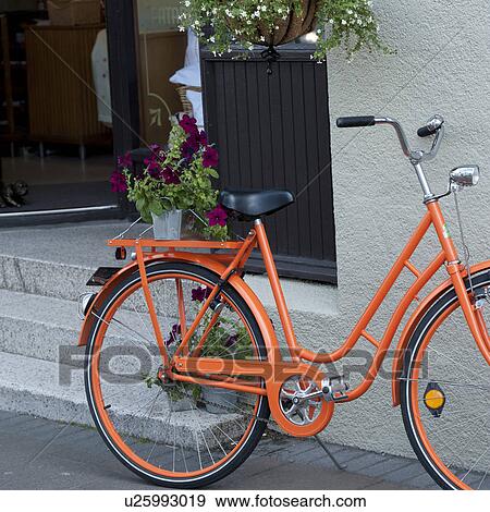 Stock Photo - Bicycle parked on city sidewalk beside flower pots. Fotosearch