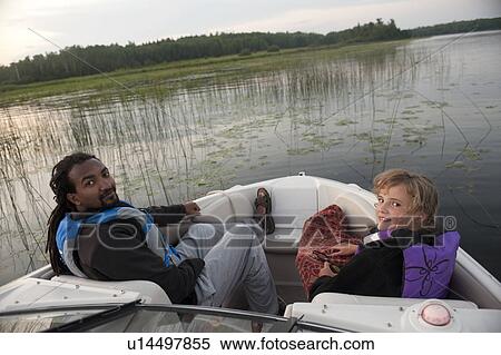 Blond girl with an Africian American man at the bow of a motor boat in Lake of the Woods, Ontario View Large Photo Image Stock Photography - Blond girl with an Africian American man at the bow of a motor boat in Lake of the Woods, Ontario. Fotosearch