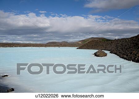 Blue lagoon with rocky coastline under a bright blue clouded sky View Large Photo Image Stock Photograph - Blue lagoon with rocky coastline under a bright blue clouded sky. Fotosearch