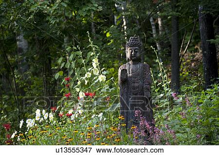 Stock Photo - Buddha statue amongst wildflowers at Lake of the Woods, Ontario. Fotosearch