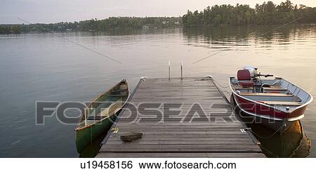 Stock Photograph - Canoe and motorboat at a dock in Lake of the Woods, Ontario. Fotosearch