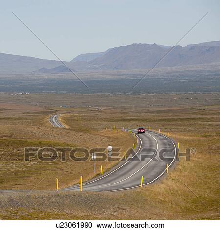 Stock Image - Car on meandering highway through countryside towards distant mountains. Fotosearch