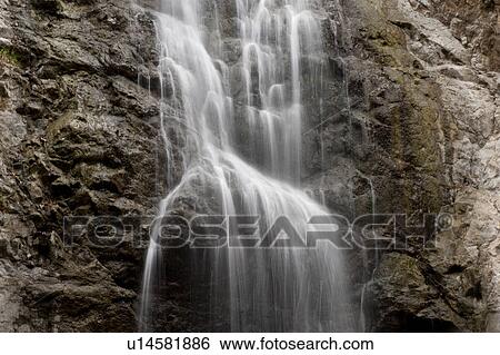 Stock Photograph - Cascading waterfall over steep rock face. Fotosearch