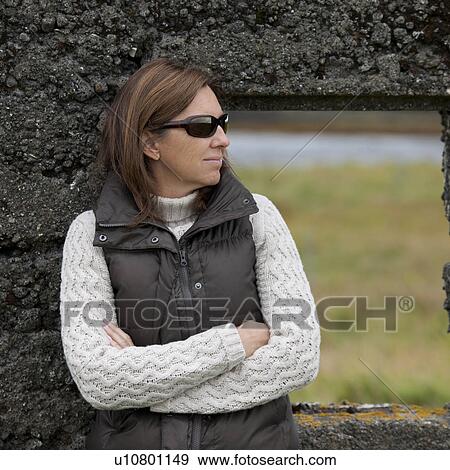 Casual portrait woman in sunglasses, down vest, and knit sweater, before rugged stone window frame View Large Photo Image Stock Photo - Casual portrait woman in sunglasses, down vest, and knit sweater, before rugged stone window frame . Fotosearch